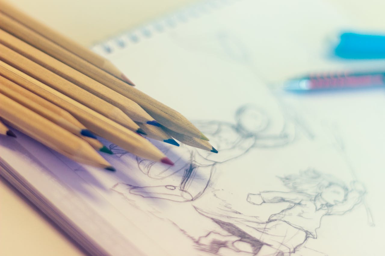 Close-up of colored pencils on sketch-filled notepad, perfect for creativity concepts.